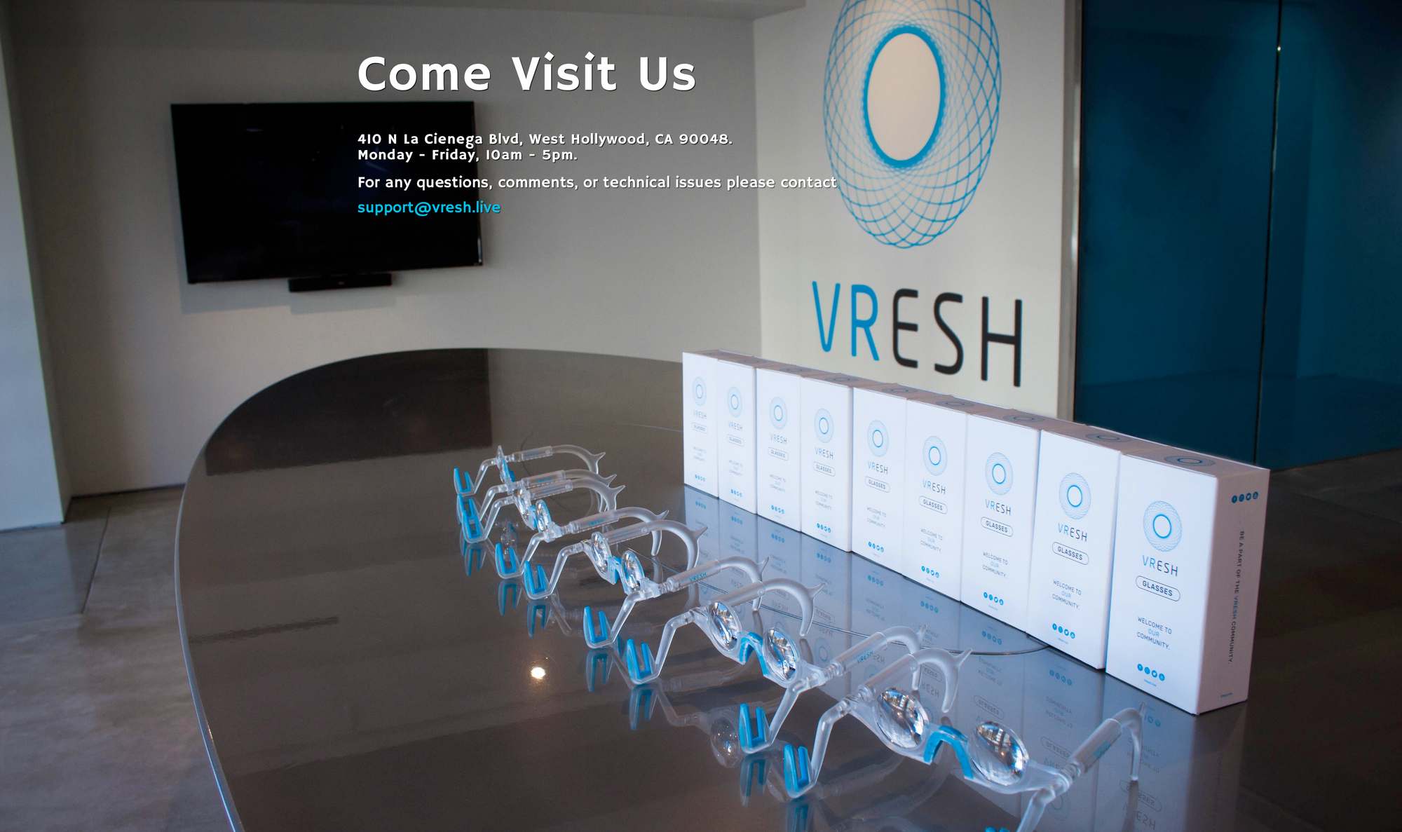 five pairs of special glasses laid out on a table, in front of nine glasses boxes. logo visible in background.